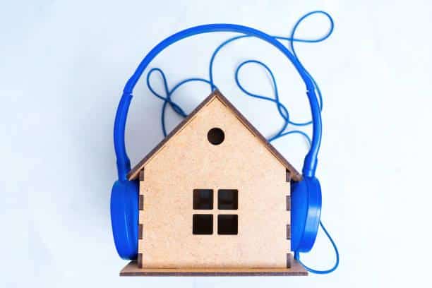 Cuffie blu e casa di legno - Simbolo dell'isolamento acustico domestico